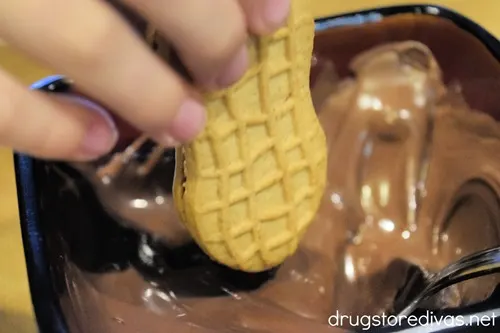 A Nutter Butter cookie being stuck into melted chocolate.