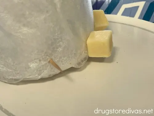 A foam cone with a toothpick sticking out and two pieces of cheese at the bottom of the cone.