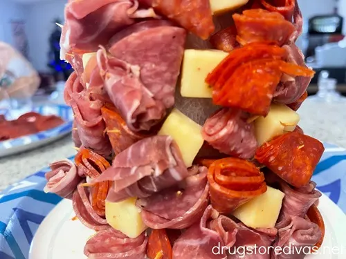 A foam cone with cheese cubes and folded meat around it.