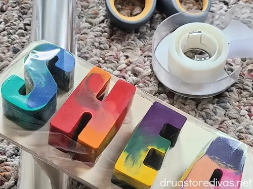 Cellophane, scissors, tape, and crayons spelling out the name SHEA.