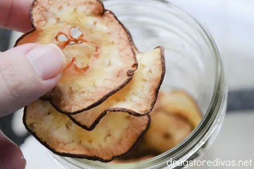 A hand adding dehydrated pears into a mason jar.