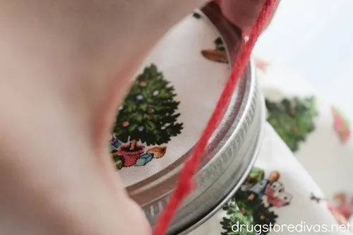 A piece of red yarn being lopped around a mason jar.