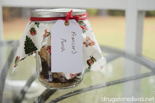 A mason jar with dried fruit in it and fabric on it and a tag with the words "Prancer's Punch" attached to it.
