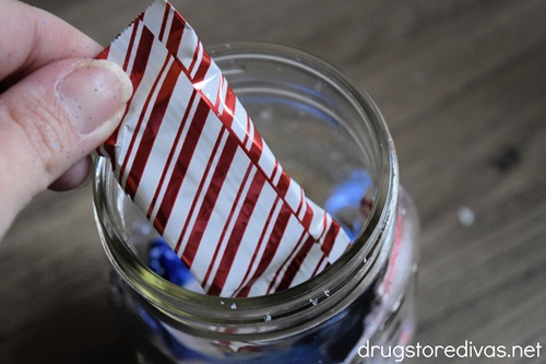 A red and white striped chocolate being put in a mason jar.