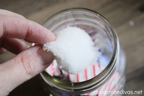 A cotton ball being put in a mason jar.