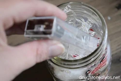 Battery operated fairy lights being put in a mason jar.