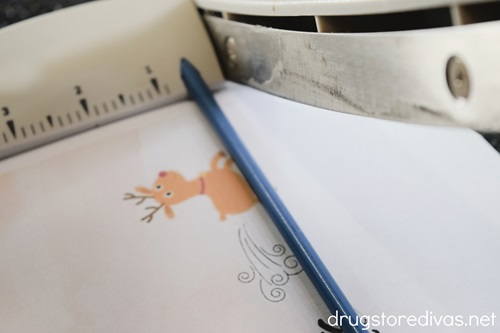 A paper trimmer cutting a printable with a reindeer photo on it.