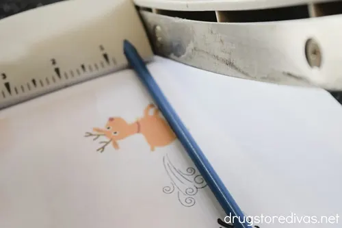 A paper trimmer cutting a printable with a reindeer photo on it.