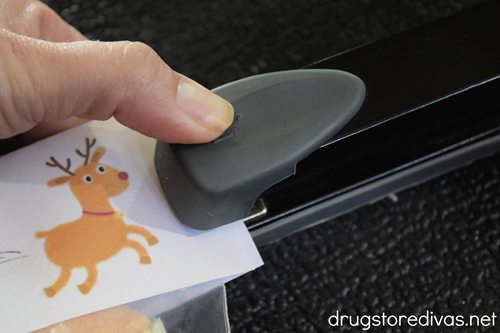 A stapler stapling a paper with a reindeer image on it.