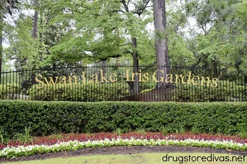 A metal sign in a park that says "Swan Lake Iris Gardens" in Sumter, SC.