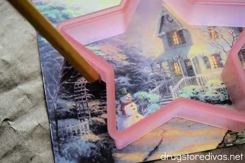 A pink star shaped cookie cutter on top of a card with a winter scene on it.