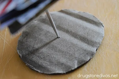 A sharp wooden dowel on top of a circle of cardboard.
