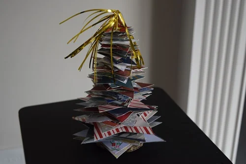 A DIY Christmas Card Tree on a black table.