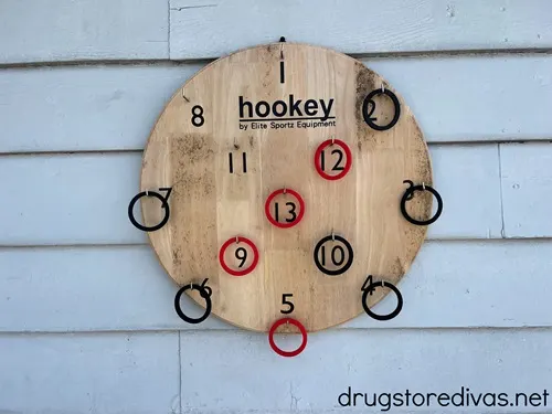 A wooden hookey game on a wall, which is a large wooden circle with numbers on it and rings around some of the numbers.