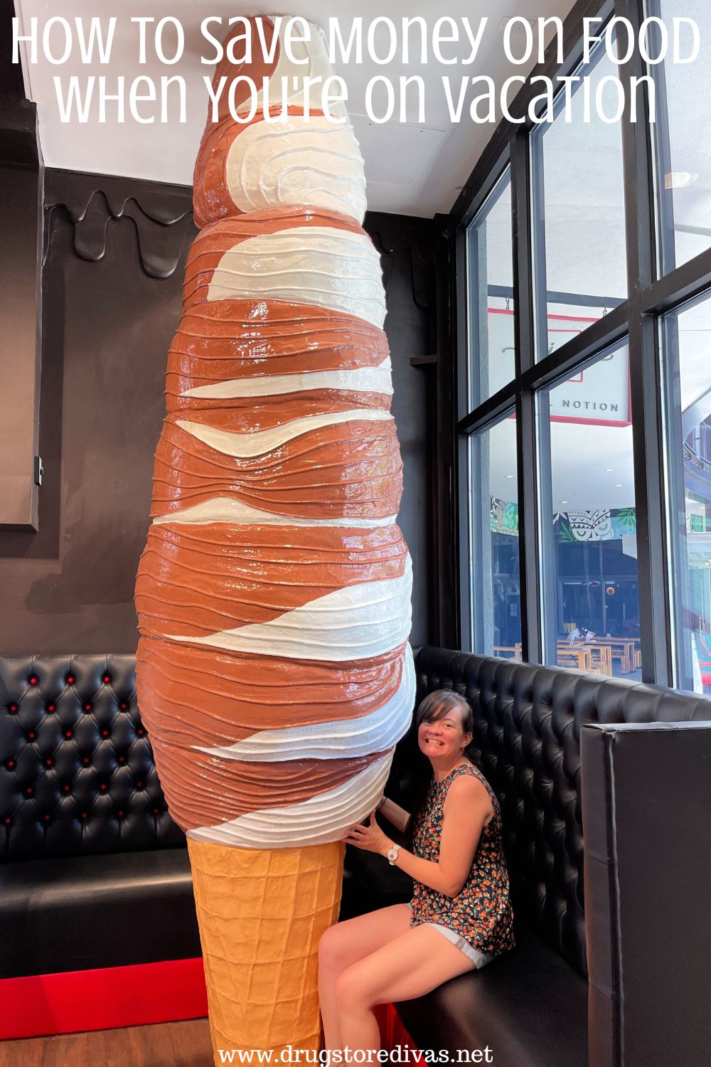 A woman sitting next to a giant, floor to ceiling, ice cream cone with the words 