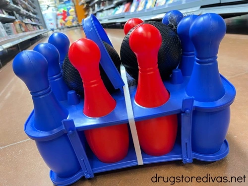 A red and blue lawn bowling set in a package on the floor in a store.