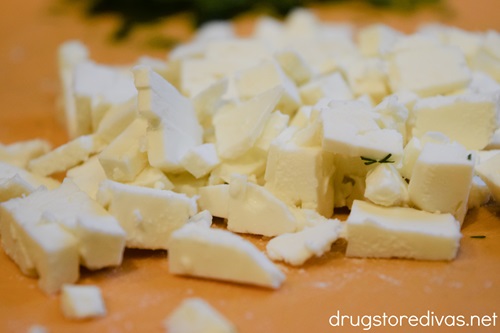Cut feta cheese on an orange cutting board.