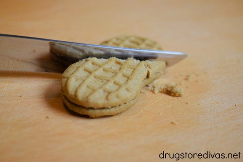 A knife cutting a Nutter Butter cookie in half.