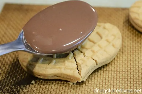 A spoon with melted chocolate over Nutter Butter cookies.