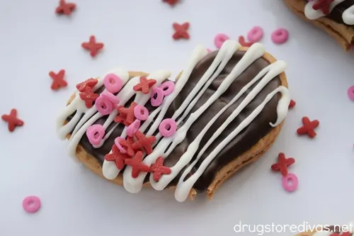 A decorated Nutter Butter Cookie Heart on a white tray with red and pink XO sprinkles around it.