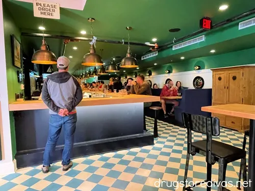 A man standing at a bar and some tables inside Ponysaurus Brewing in Wilmington, NC.