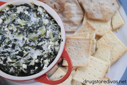 Spanakopita dip in a red mini Dutch oven surrounded by crackers.