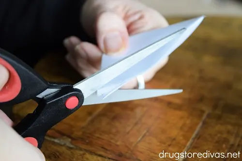 A pair of scissors cutting a white paper.