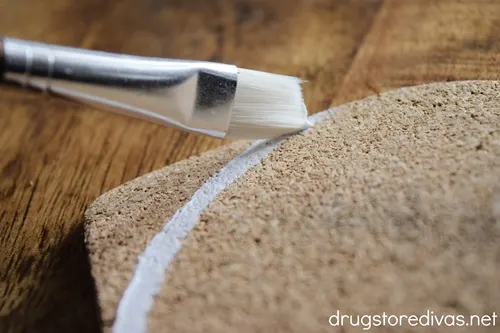 A white line being painted onto a football-shaped piece of cork.