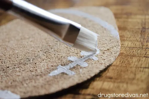 White laces being painted on a football-shaped coaster.