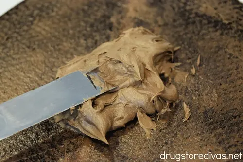 An icing knife putting a pile of icing on a brownie.