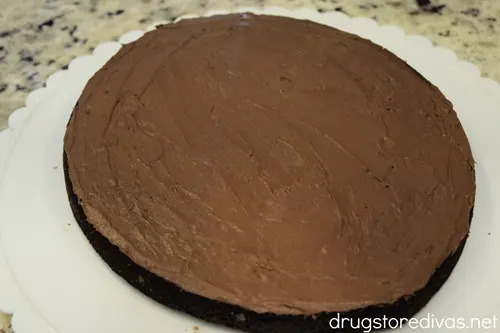 An iced football-shaped brownie on a white scalloped plate.