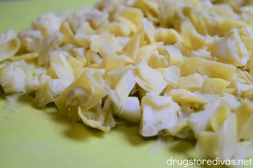 Chopped artichoke pieces on a green cutting board.
