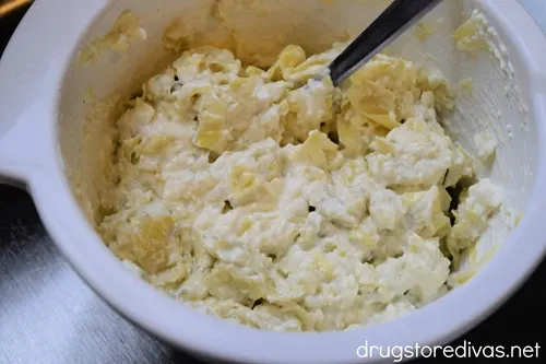 Artichoke dip in a white bowl.