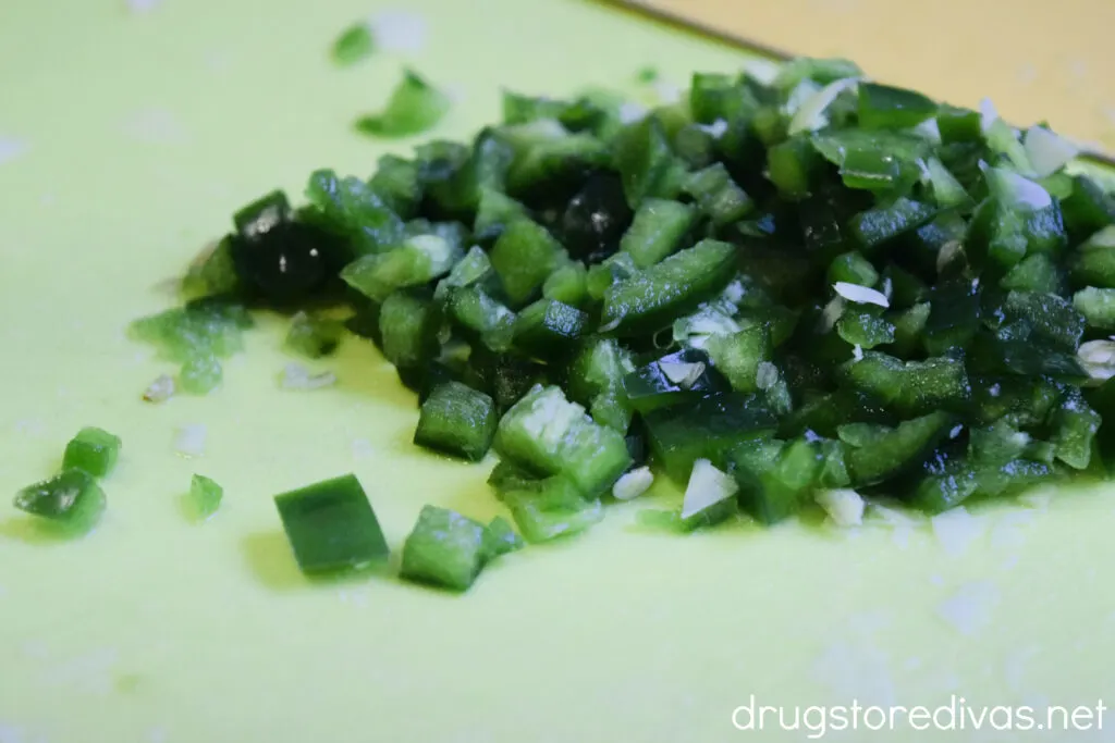 Chopped jalapeno peppers on a green cutting board.
