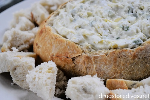 Jalapeno artichoke dip in a bread bowl surrounded by bread cubes.