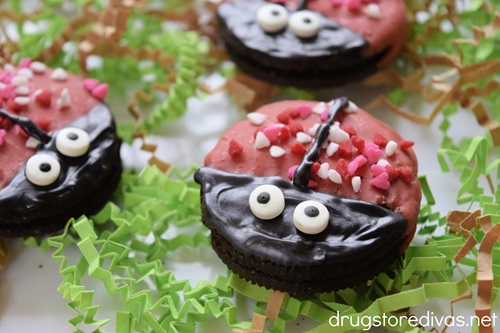Three ladybug OREO cookies on top of green and brown paper shred.