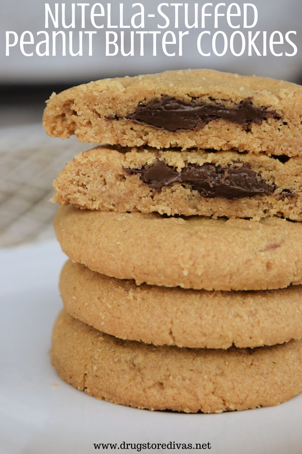 Five peanut butter cookies stacked on top of each other with the top two cut open to show chocolate inside and the words 