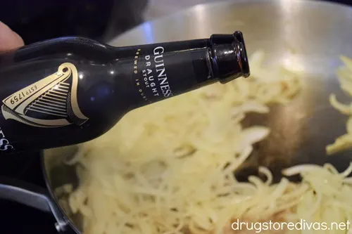 A Guinness beer about to be poured on sliced onions in a pan.