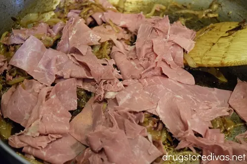 Slices of corned beef in a pan with onions.