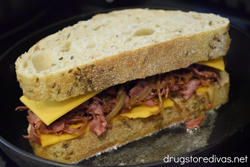 A corned beef and cheese sandwich in a pan.