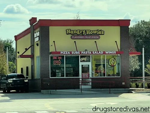The outside of a Hungry Howie's restaurant with a car in the drive through.