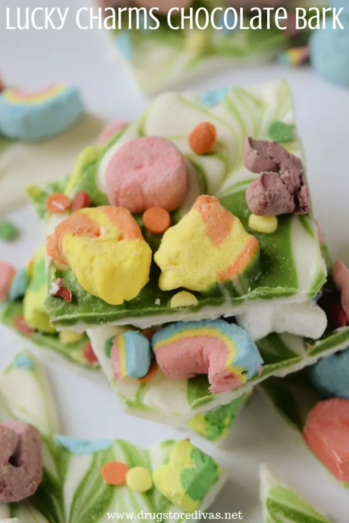 Pieces of white and green chocolate with colorful marshmallows on top and the words "Lucky Charms Chocolate Bark" digitally written on top.