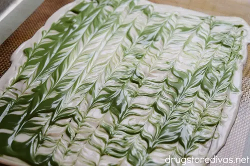 Swirls of green chocolate all over the top of melted white chocolate.