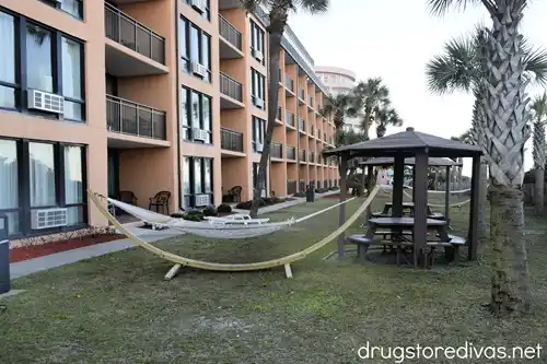 A hammock and pergola on grass outside a hotel in Myrtle Beach, SC.