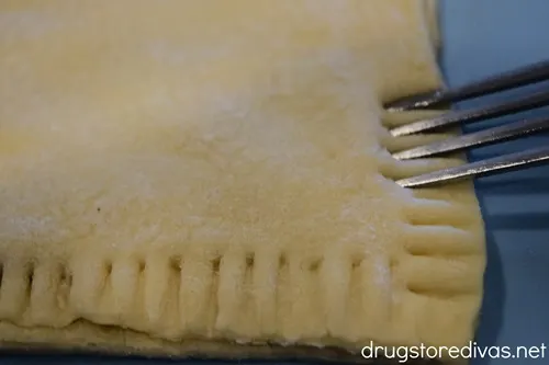 A fork crimping edges of puff pastry.