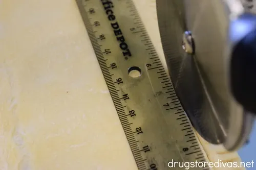 A pizza cutter cutting puff pastry.