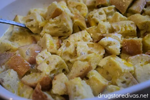 Bread cubes and a spoon in a white casserole pan.