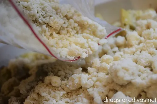 Crumb topping in a bag being poured into a casserole pan.