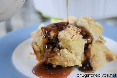 Syrup being poured on top of a piece of French Toast Casserole on a blue and white plate.