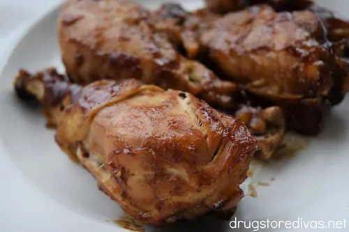 Slow cooker BBQ chicken drumsticks on a white plate.